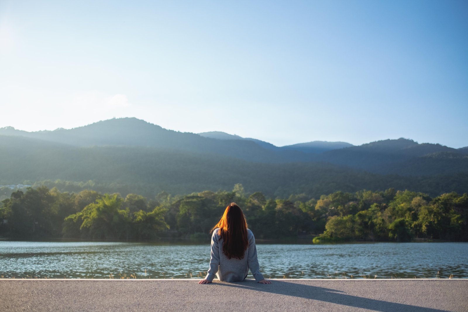 a-woman-sitting-alone-by-the-lake-looking-at-the-m-2024-11-28-04-36-50-utc